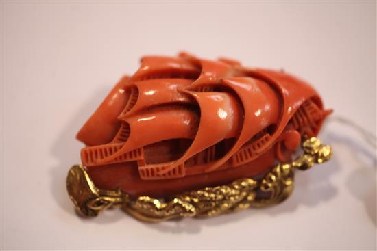 A Chinese 14ct gold mounted carved coral brooch, modelled as a masted ship at sea, 2.25in.